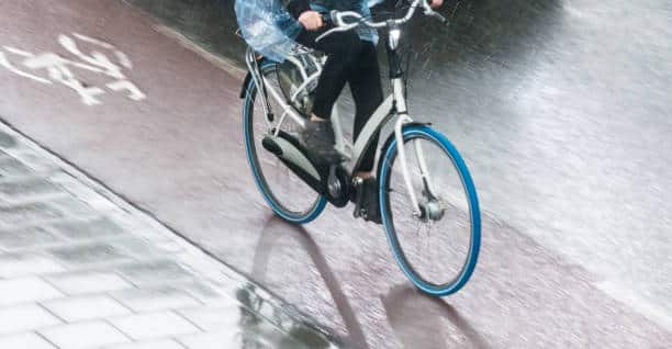 Cycling in the rain with raincoat on cycle path